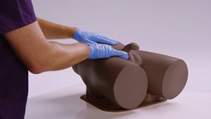 Standard clinical male pelvic trainer in dark skin tone that simulates testicular pathologies for nurses and healthcare practitioners 