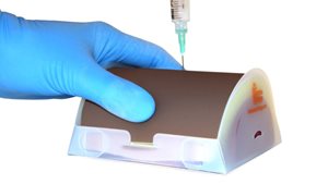 The Vaccine IM Injection Trainer in dark skin tone that simulates the administration of vaccines, such as Covid-19, via the intramuscular route.